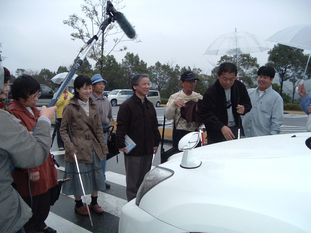 ハイブリッド車見学会の写真です。
エンジン音が静かで、『こんなに接近しているとはびっくりだよ！』と驚く会員です。
逆にエンジン音が静かすぎて、車の存在を察知できないという怖さ感じます！